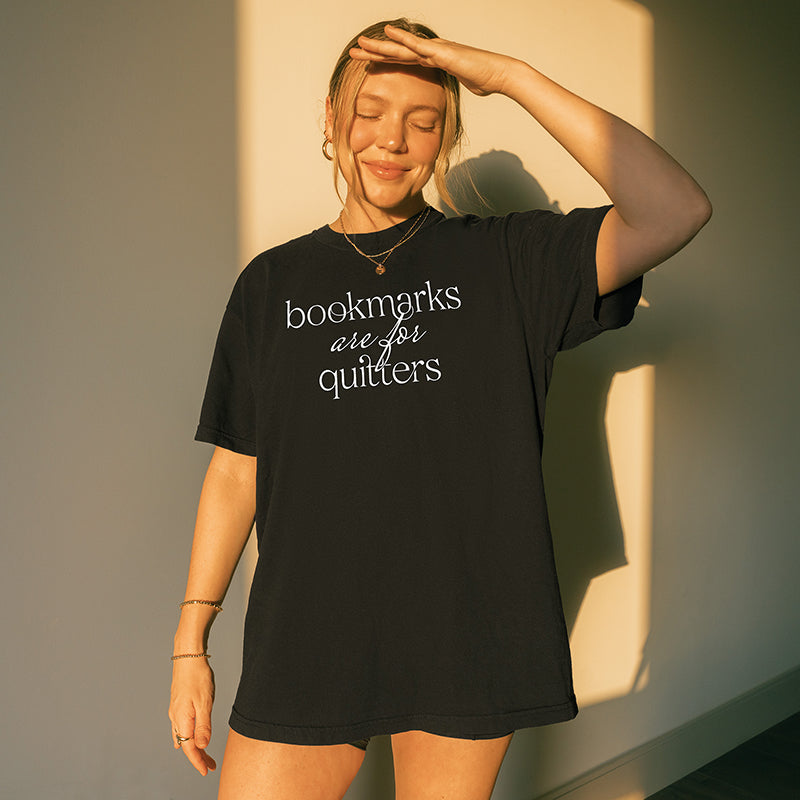Woman wearing black “Bookmarks Are for Quitters” tee indoors with relaxed oversized style – bookish graphic tee for readers