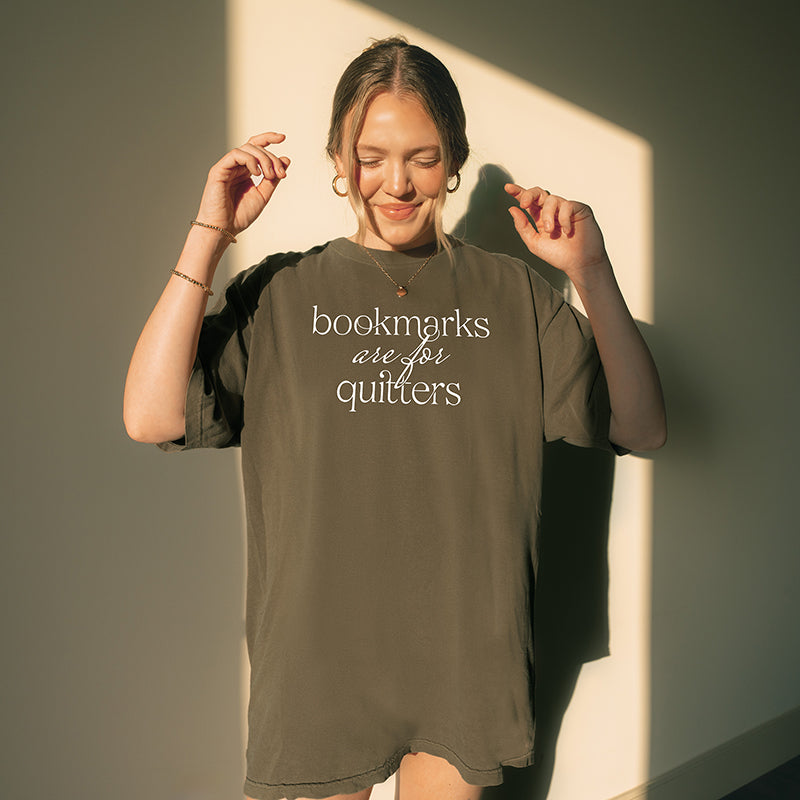 Woman wearing pepper “Bookmarks Are for Quitters” tee indoors – cozy oversized reading graphic tee for book lovers