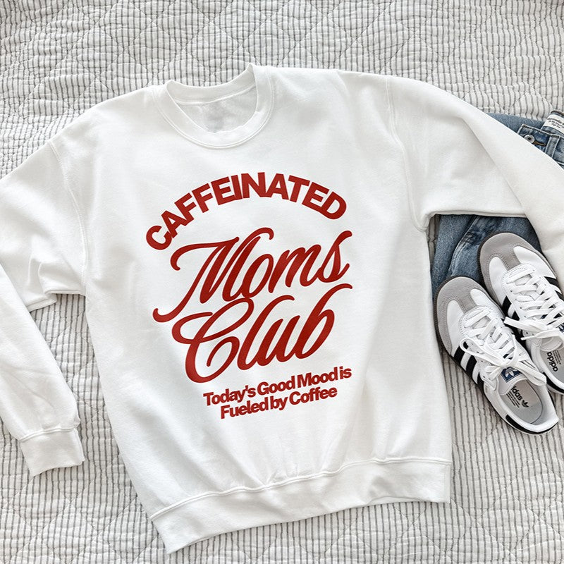 Caffeinated Moms Club white sweatshirt with bold red retro text reading “Today’s Good Mood Is Fueled by Coffee,” styled on a bed with jeans and sneakers.