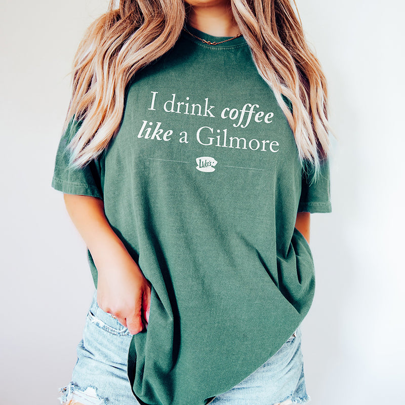 Woman wearing I Drink Coffee Like A Gilmore graphic tee in light green, cozy Gilmore Girls inspired shirt for coffee lovers
