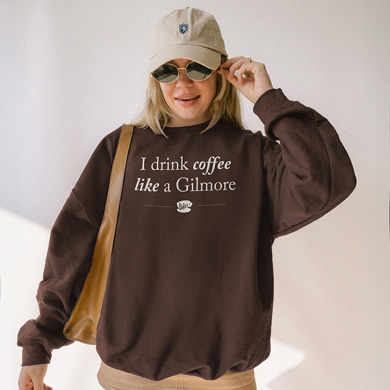 Model wearing dark chocolate “I Drink Coffee Like a Gilmore” sweatshirt styled with skirt, baseball cap, and sunglasses – Stars Hollow inspired look
