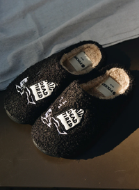 Black fuzzy slippers with embroidered “Dead Tired” design, fleece lining, and rubber sole; cozy unisex loungewear perfect for Halloween or everyday exhaustion.