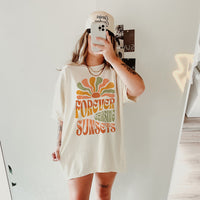 Model wearing Forever Chasing Sunsets tee in ivory — boho summer graphic t-shirt for women