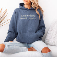 Woman wearing heather dark navy “I Put My Book Down To Be Here” hoodie – cozy book lover sweatshirt for readers and introverts