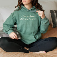 Woman wearing heather dark green “I Put My Book Down To Be Here” hoodie – funny bookish pullover for avid readers