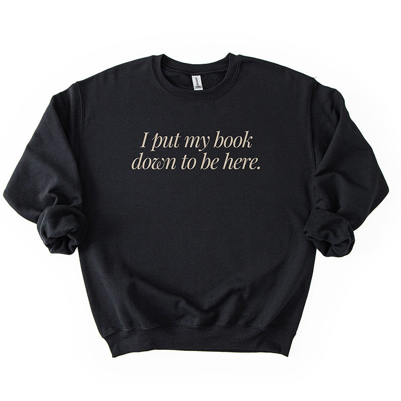 Flatlay of I Put My Book Down To Be Here Sweatshirt in black – funny bibliophile sweatshirt.