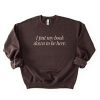 Flatlay of I Put My Book Down To Be Here Sweatshirt in dark chocolate – witty reading sweatshirt.