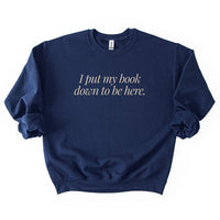 Flatlay of I Put My Book Down To Be Here Sweatshirt in navy – cozy bookish crewneck.