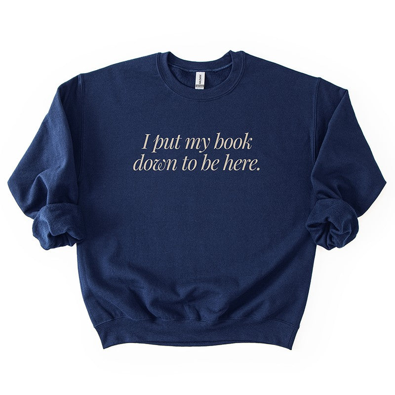 Flatlay of I Put My Book Down To Be Here Sweatshirt in navy – cozy bookish crewneck.