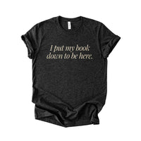 Flatlay of the I Put My Book Down To Be Here Tee in black heather – unisex funny bookish graphic tee.