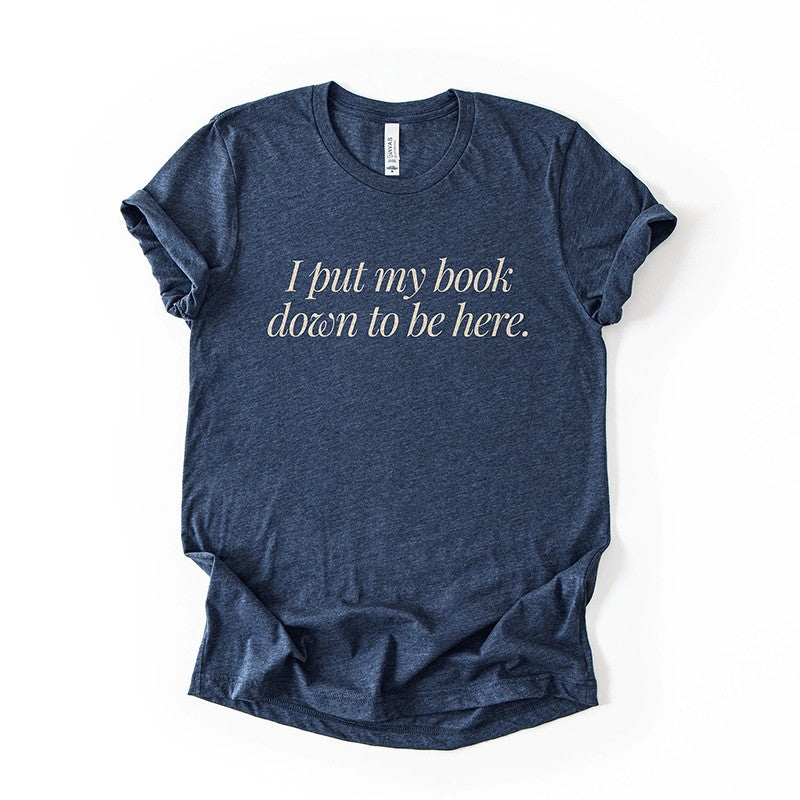 Flatlay of the I Put My Book Down To Be Here Tee in heather navy – lightweight Bella Canvas book lover shirt.