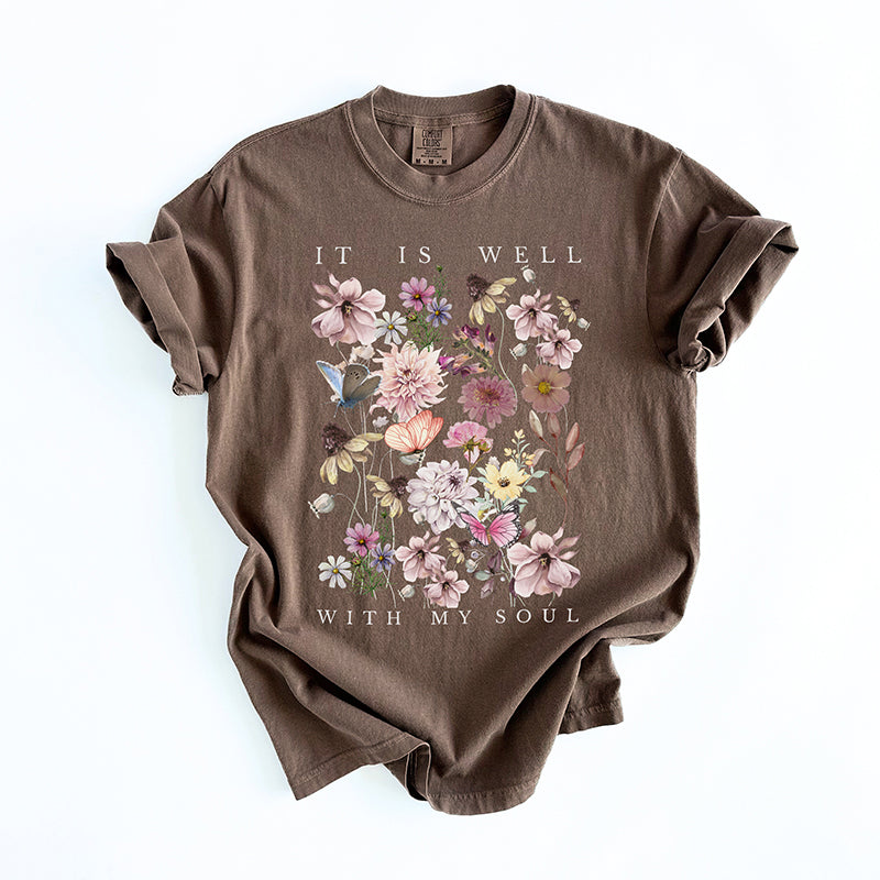 Flat lay of It Is Well With My Soul tee — hand-printed multicolor graphic on brown shirt
