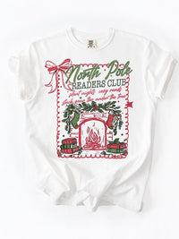 Flat lay of North Pole Readers Club Christmas book lover tee — cozy tbr holiday graphic shirt for readers