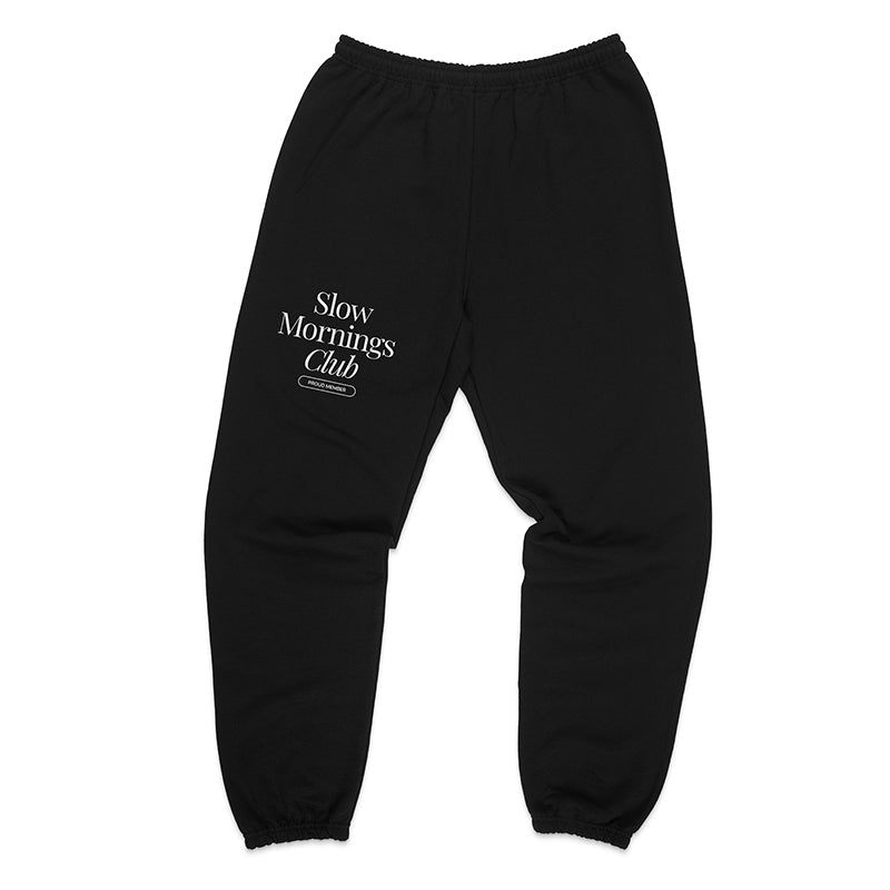Flatlay of black Slow Mornings Club sweatpants featuring Slow Mornings Club design and elastic waistband