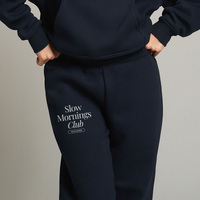 Model wearing navy Slow Mornings Club sweatpants with elastic cuffs and drawcord waistband.