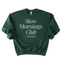 Flatlay of forest green Slow Mornings Club crewneck sweatshirt with minimalist graphic